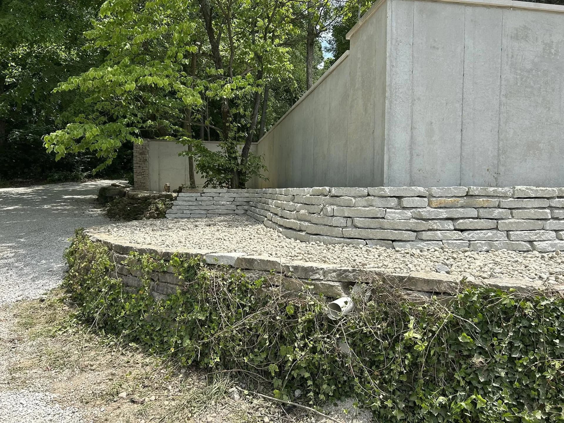 Completed limestone retaining wall and drainage stone bed along a concrete building